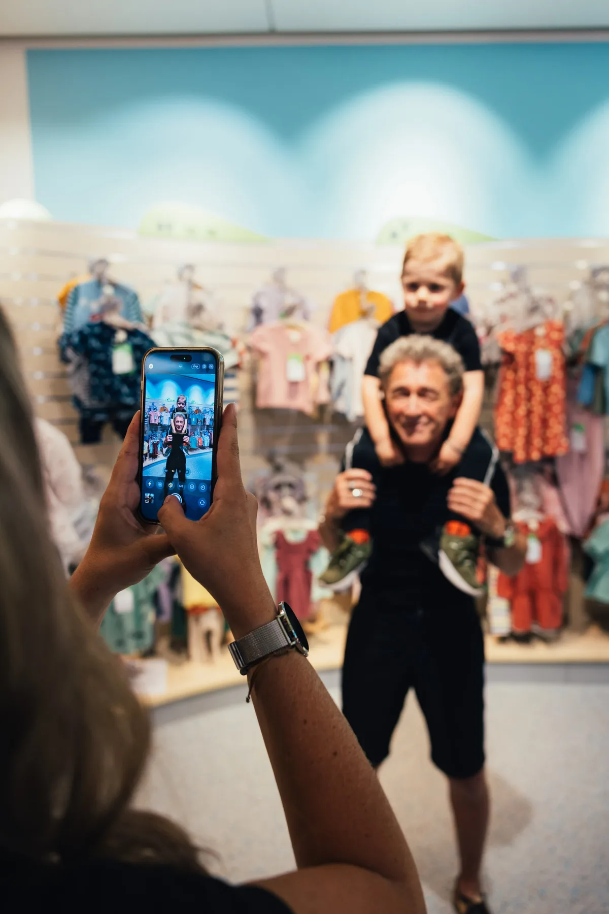 Peter Maffay trägt einen Jungen auf den Schultern, im Vordergrund fotografiert eine Frau beide mit dem Smartphone