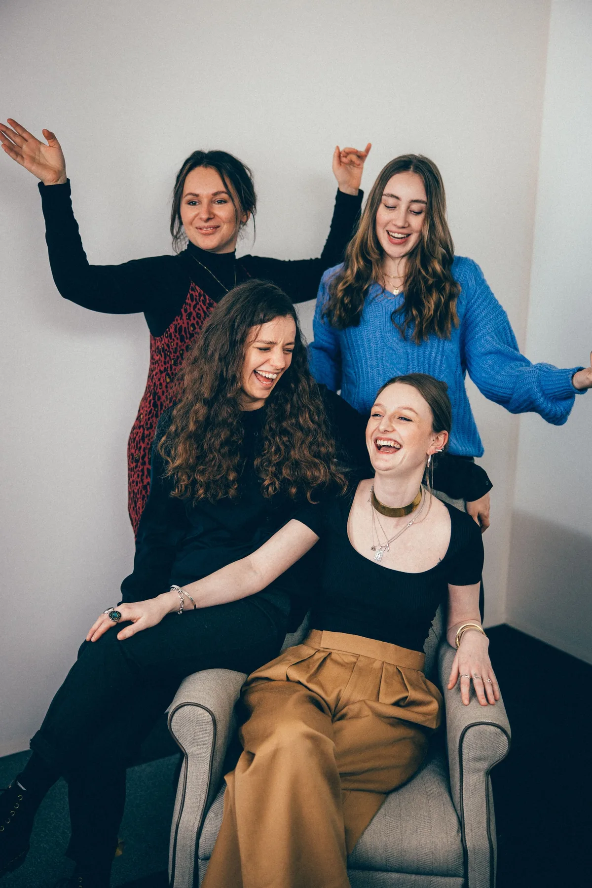 Dieselben vier Frauen auf und hinter dem Sessel lachen laut, die zwei hinteren heben die Arme