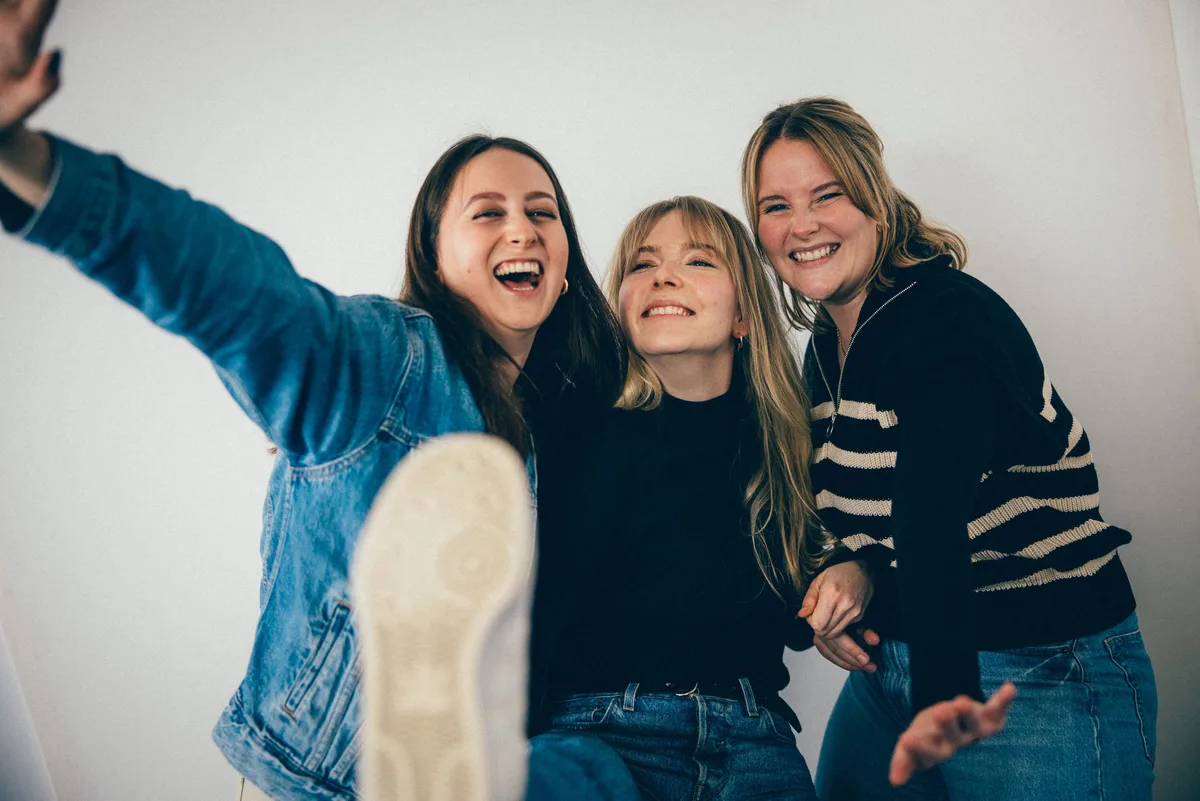 Die drei Frauen lachen ausgelassen, links reckt eine Arm und Bein, die Schuhsohle ragt ins Bild