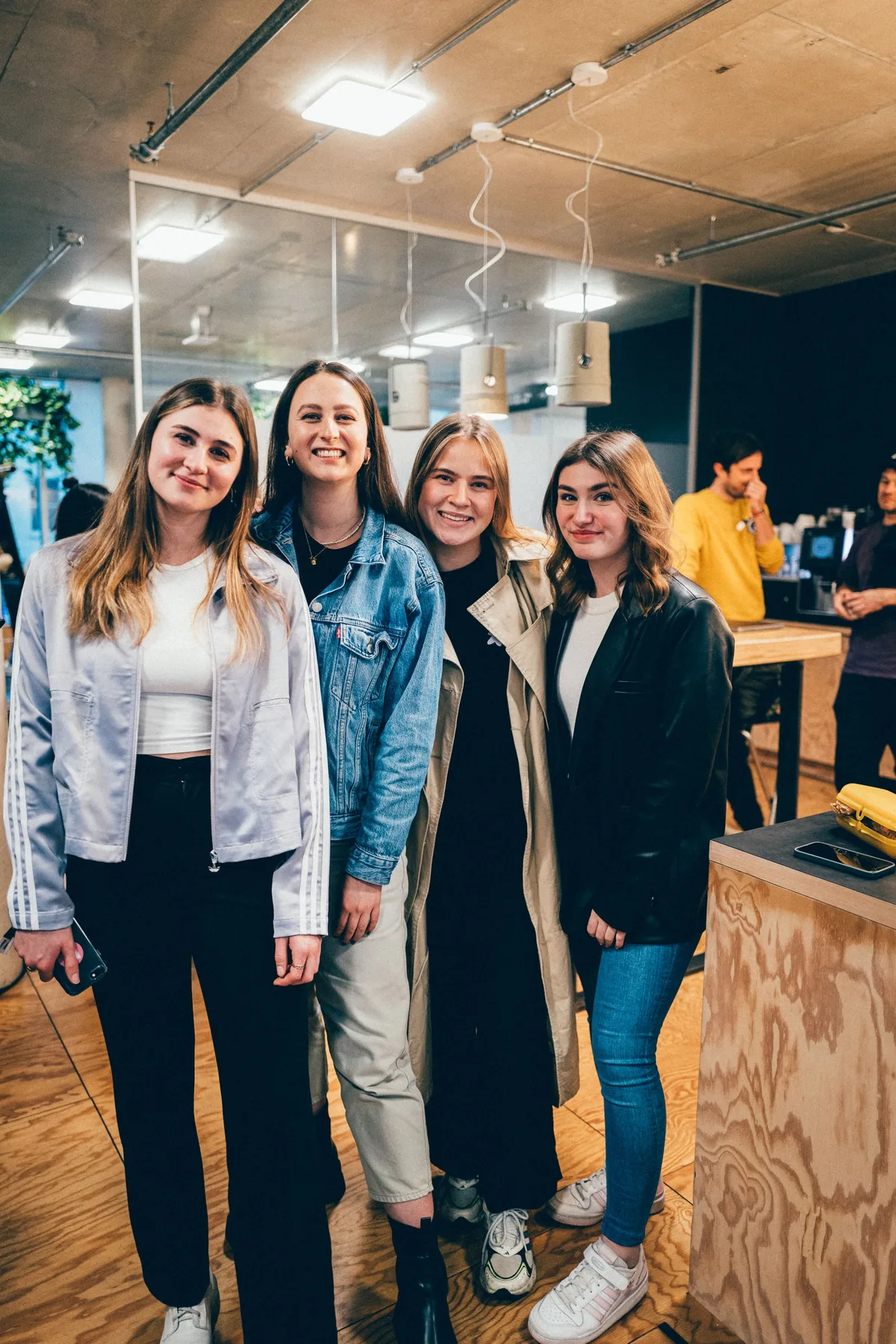 Vier junge Frauen stehen nebeneinander in der Küche, in Trainingsjacke, Jeansjacke, Trenchcoat und Lederjacke