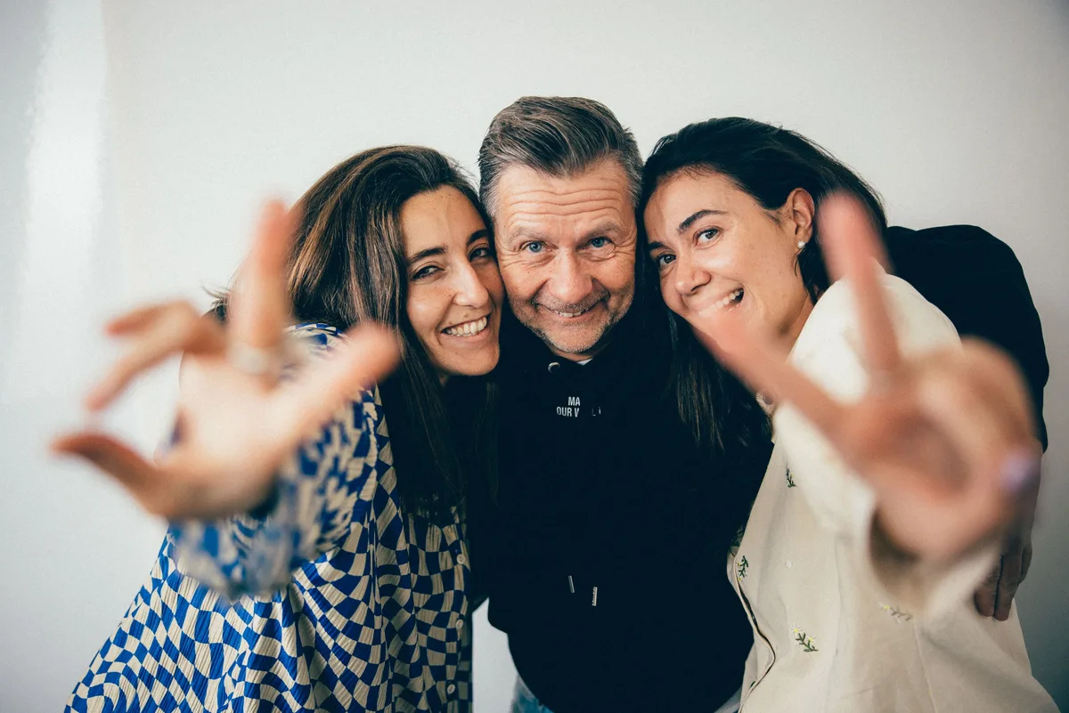 Dasselbe Trio dicht zusammen, die beiden Frauen strecken Victory-Zeichen zur Kamera, der Mann lächelt in der Mitte