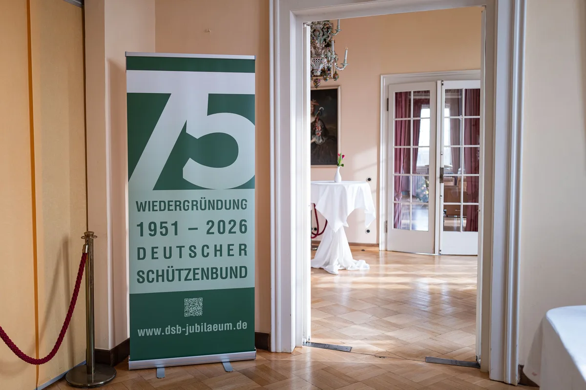 Roll-up zum 75. Jubiläum des Schützenbundes neben einer Absperrkordel, durch die offene Tür ein heller Saal mit Stehtisch