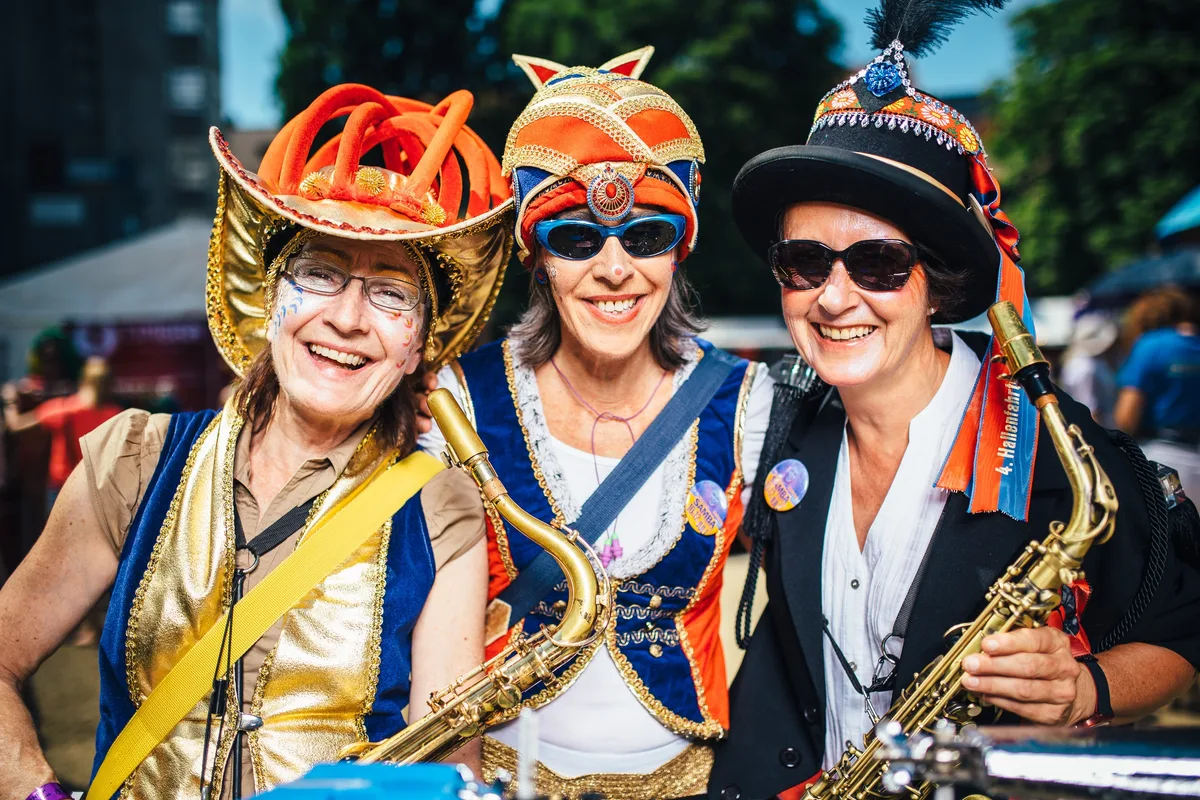 Enger Ausschnitt der drei Frauen mit goldenem Hut, orangem Turban und Federhut, Saxofone vor der Brust